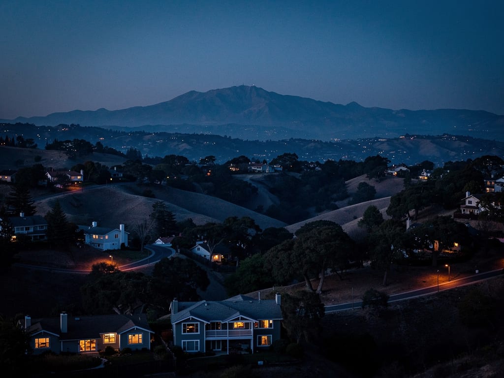 Orinda hills at dusk with scattered homes lit among oak trees and Mount Diablo on the horizon